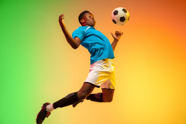 male soccer, football player training in action isolated on gradient studio background in neon light - action adult adults only ball imagens e fotografias de stock