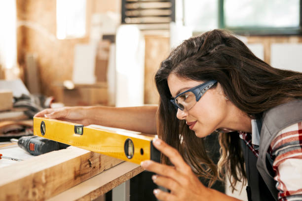 Female Carpenter looking for a curvature of a plank