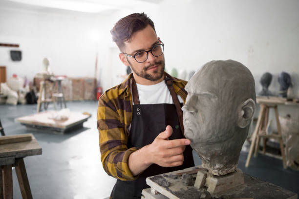 istock Male Sculptor working on a clay bust of a human head 1266974213