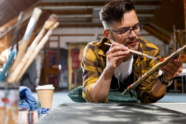 istock Young painter in a studio working on his art mixing colors 1266974307