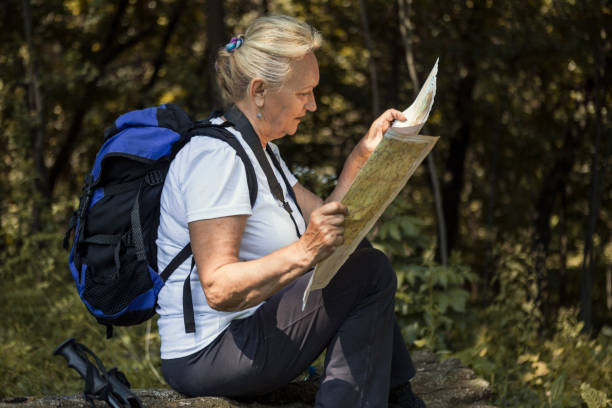 istock Mature woman hiking on mountains looking on a map 1266974437