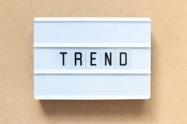 Photo of White lightbox with word trend on wood background