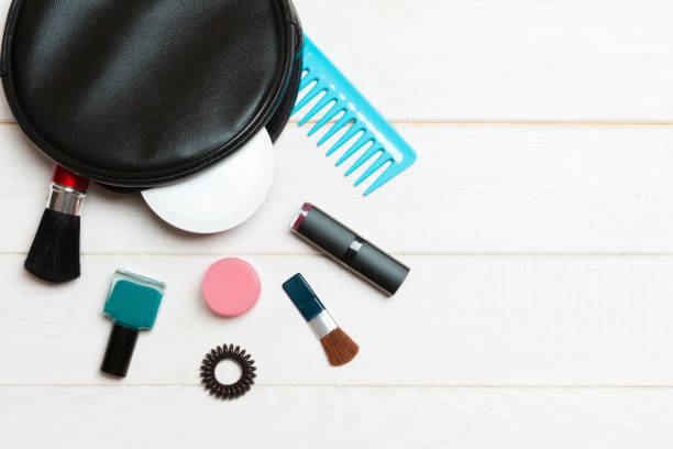 aerial view of a leather cosmetics bag with make up beauty products spilling out on wooden background. beautiful skin concept with copy space - pampering nail polish make up spilling imagens e fotografias de stock
