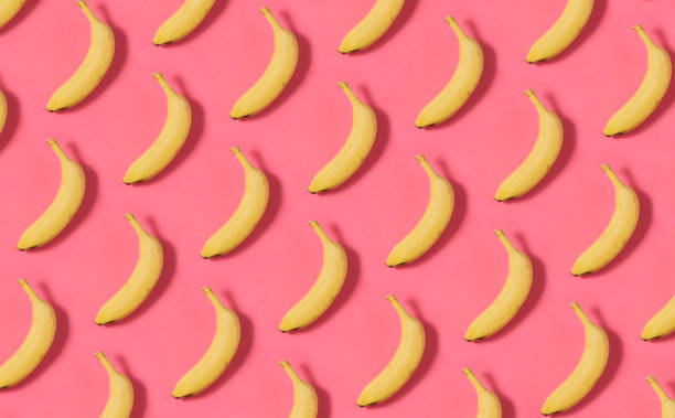 Banana Pattern on Pink Background Bananas in a row on yellow background repetition photos stock pictures, royalty-free photos & images