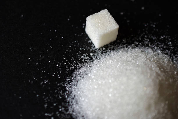 istock Scattered sugar in a pile and refined sugar cubes on a black background 1266978670