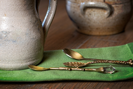 Display of antique pottery and eating utensils with a green napkin