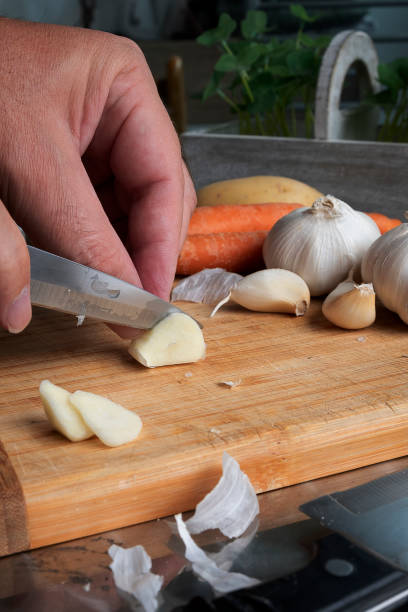 istock Peeling and cutting garlic on a wooden board. Man's hands. 1266982925