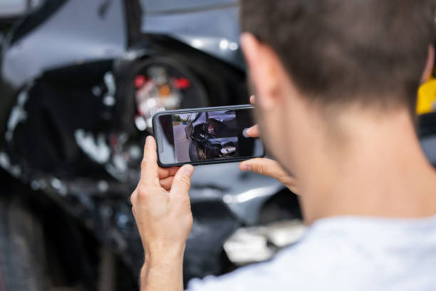 conductor masculino tomando foto del coche dañado después de accidente para la reclamación de seguro en el teléfono móvil - accidente de automóvil fotos fotografías e imágenes de stock