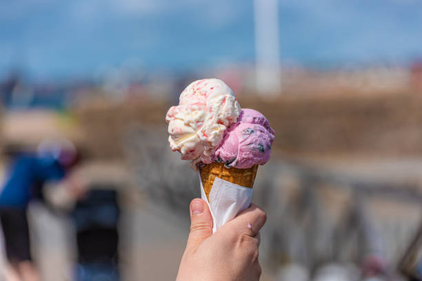 istock Pink and white ice cream in a cone melting in the sun 1266983184