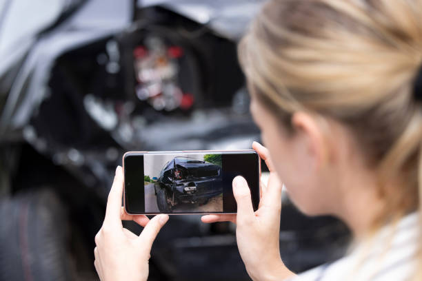 conductora mujer tomando foto del coche dañado después de accidente para la reclamación de seguro en el teléfono móvil - accidente de automóvil fotos fotografías e imágenes de stock