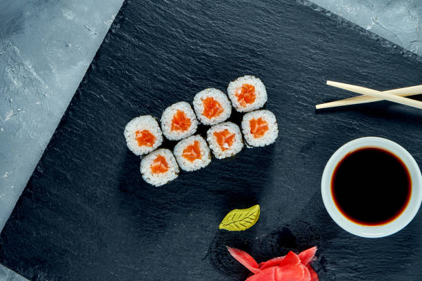istock Appetizing maki sushi with salmon on a black slate board 1266984489