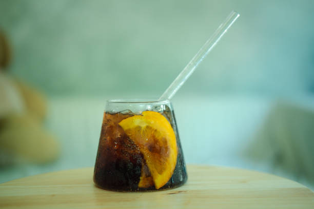 istock Cool soft drink with orange slices inside glass on wooden table 1266986058