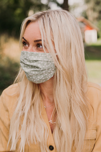 Content happy woman wearing a protective mask in times of corona
Mid adult woman earing a textiel mask with pocket for filter
Photo taken outdoors in summer
