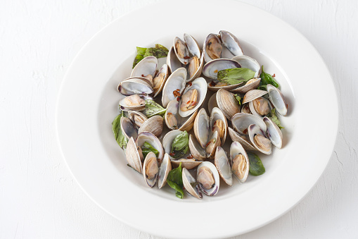A bowl of fresh steamed clams with fresh basil and red pepper flakes