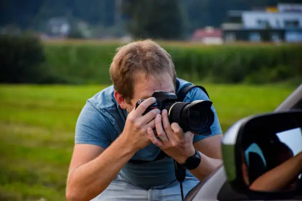 Photo of A professional photographer photographs a car with models for advertising.