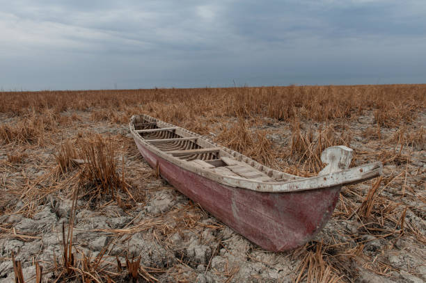 A traditional Marsh Arab boat lies idle on dry and cracked Marsh in the Central Marshes of Southern Iraq
