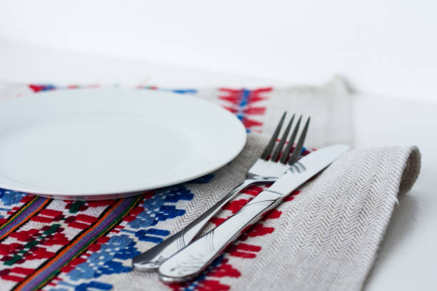 istock Table setting for dinner: a plate, a fork, a knife on a woven cloth napkin with an embroidered pattern,  traditional handmade in Ukraine 1266992134