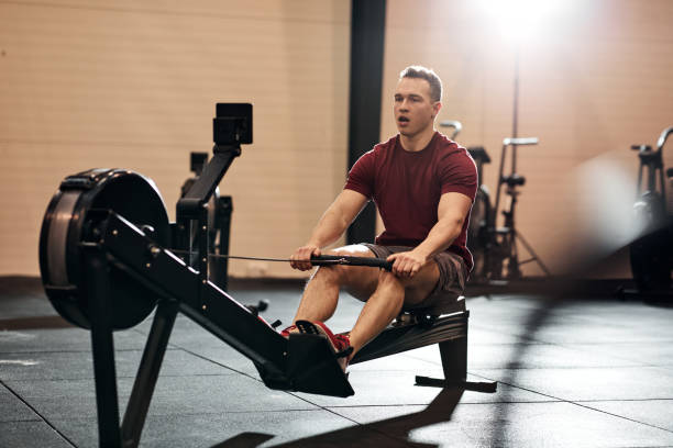 istock Young man exercising on a rowing machine at the gym 1266993338