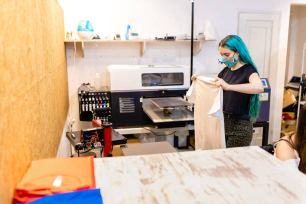 istock Diligent female worker preparing cotton T-shirt for digital printing at her modern workshop 1266995101