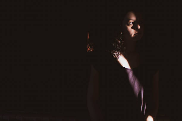 istock young woman on black background with light and shadow on face 1266996545