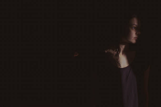 istock young woman on black background with light and shadow on face 1266996559