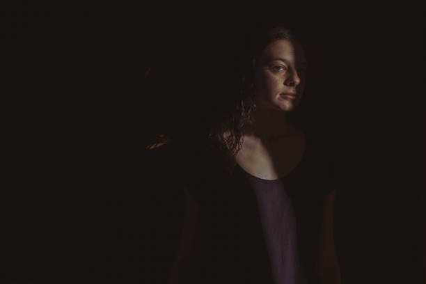 istock young woman on black background with light and shadow on face 1266996565