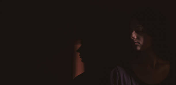 istock young woman on black background with light and shadow on face 1266996572