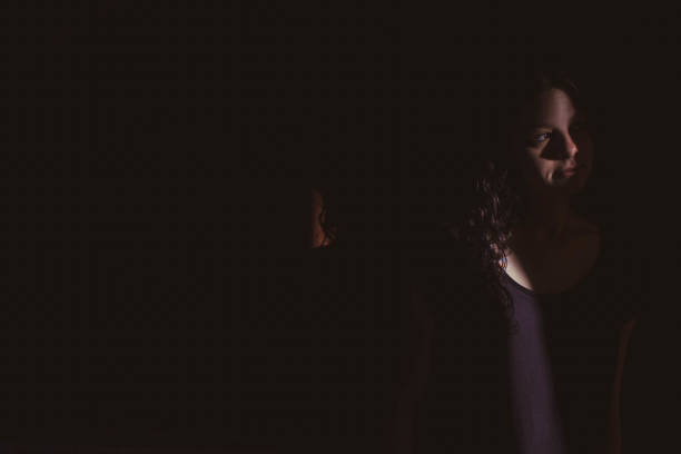 istock young woman on black background with light and shadow on face 1266996575