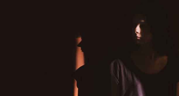 istock young woman on black background with light and shadow on face 1266996578