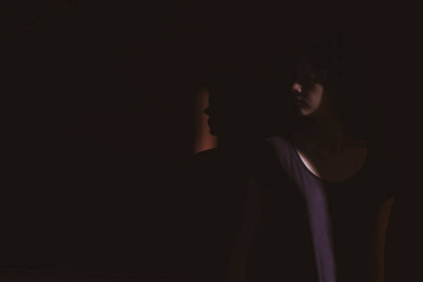 istock young woman on black background with light and shadow on face 1266996582