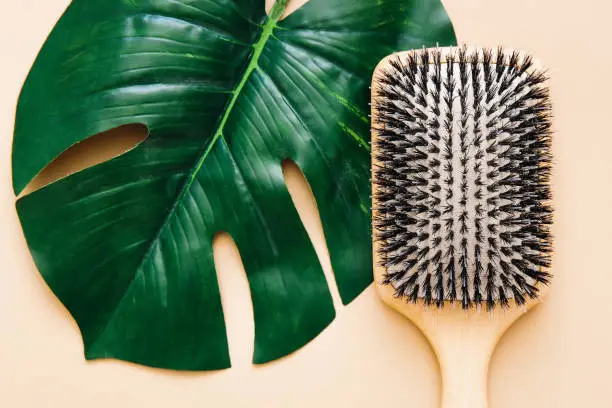 Hair care concept. Wooden hairbrush with natural bristles, lies on beige background. Spa care. Flat lay.