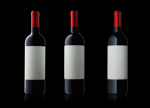 Collection of bottles of red Italian wine on black background.