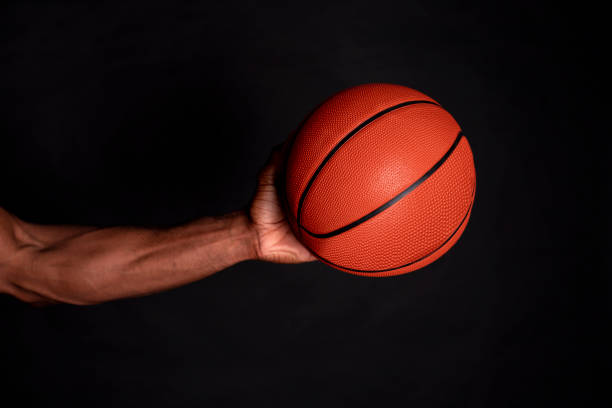 istock african man hands holding a basketball, black background 1266998613
