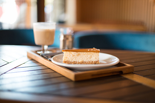 Slice of New York cheesecake on a plate. Delicious smooth cheesecake with caramel. Breakfast in the cafe, morning coffee.