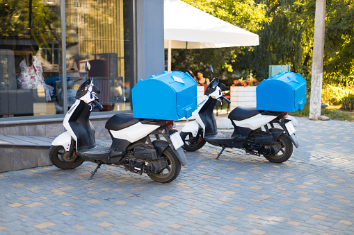 Motorcycle with a trunk is parked in the parking lot awaiting order. Delivery concept
