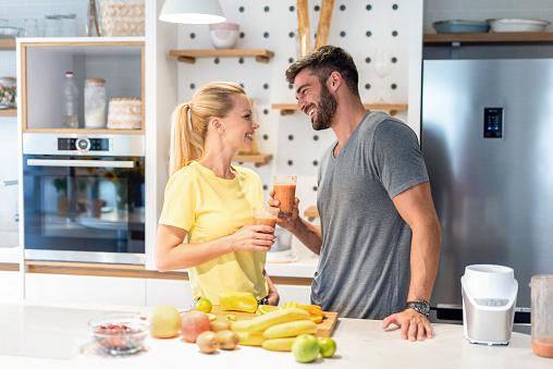 Happy young couple drinking healthy shakes in the kitchen.