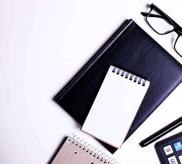 istock On a white table are a calculator, a black pen, a notebook and a flower in a pot. Top view close up, place for text. 1267005674