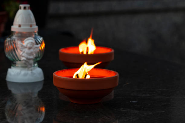 Traditional burning grave candles and decorative one on a black marble grave during All Souls' Day with copy space