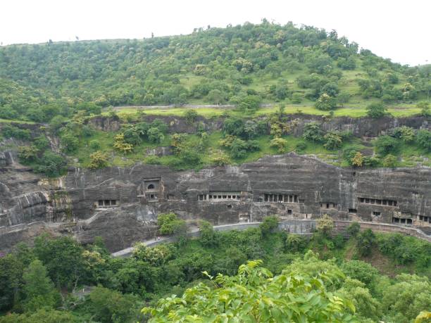 The ancient Ajanta caves on a green hill Landscape of the ancient Ajanta Caves on a green hill full of trees near Aurangabad in Maharashtra, India. ajanta caves stock pictures, royalty-free photos & images