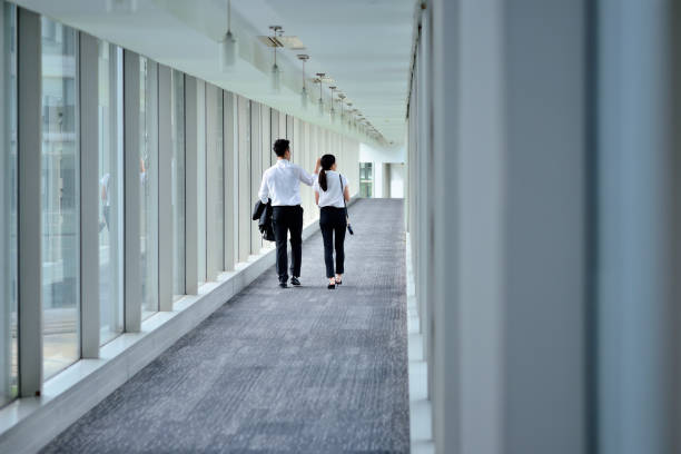 istock Rear View of Two Colleagues Talking and Walking at Aisle 1267008370