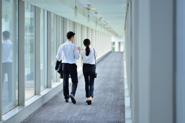 istock Rear View of Two Colleagues Talking and Walking at Aisle 1267008382