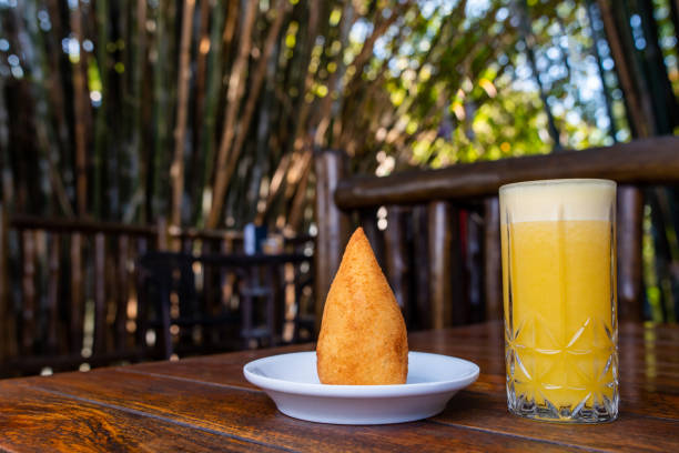 brazilian snack "coxinha" and orange juice on wood table - breadcrumb navigation imagens e fotografias de stock