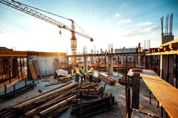 Experienced engineer explaining the problems in construction works - development after recession Construction industry concept - architects and engineers discussing work progress between concrete walls, scaffolds and cranes. construction stock pictures, royalty-free photos & images