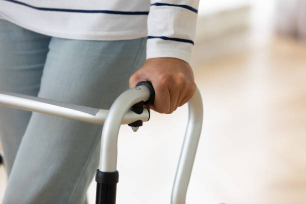 istock Older injured woman with walking equipment trying making steps. 1267012075