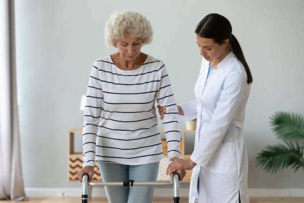 istock Medical worker helping older mature disabled woman walking with frame. 1267012082