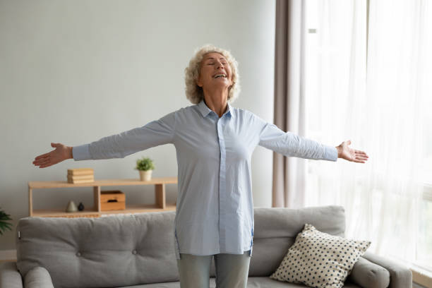 腕を伸ばして立っている先輩退職した女性。 - praying joy indoors lifestyles ストックフォトと画像