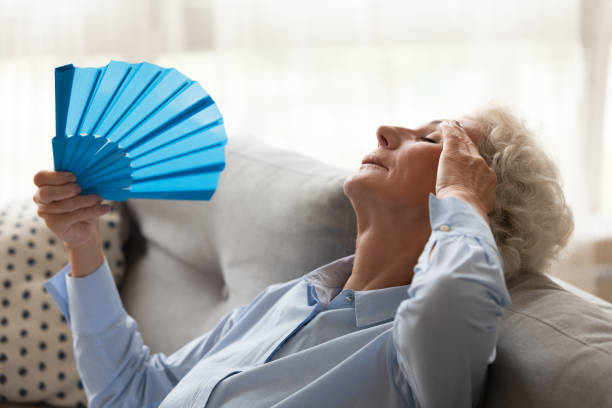 istock Overheated mature older woman using paper fan. 1267013565