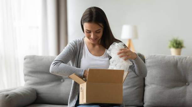 istock Happy young pretty woman unwrapping cardboard box. 1267013577