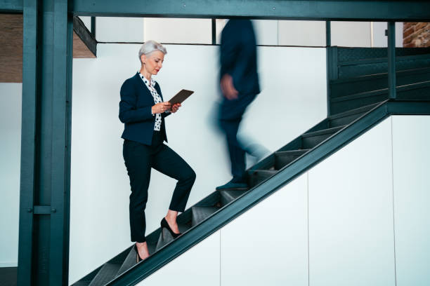 Businesswoman using digital tablet on staircase in the office.