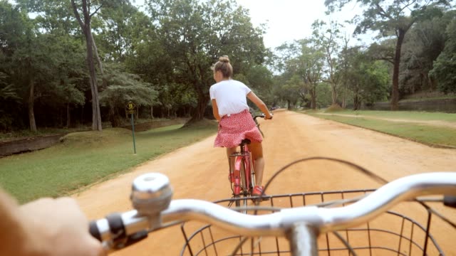 POV point of view of couple on bicycle enjoying sightseeing in Sri Lanka, man personal perspective cycling thing girlfriend in the jungle, couple having fun travel vacations
